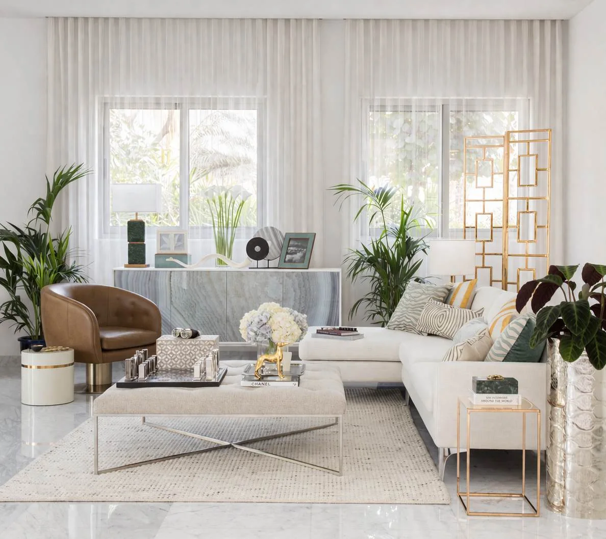 Bright furnished living room with pale sofa, armchairs and full-height curtains