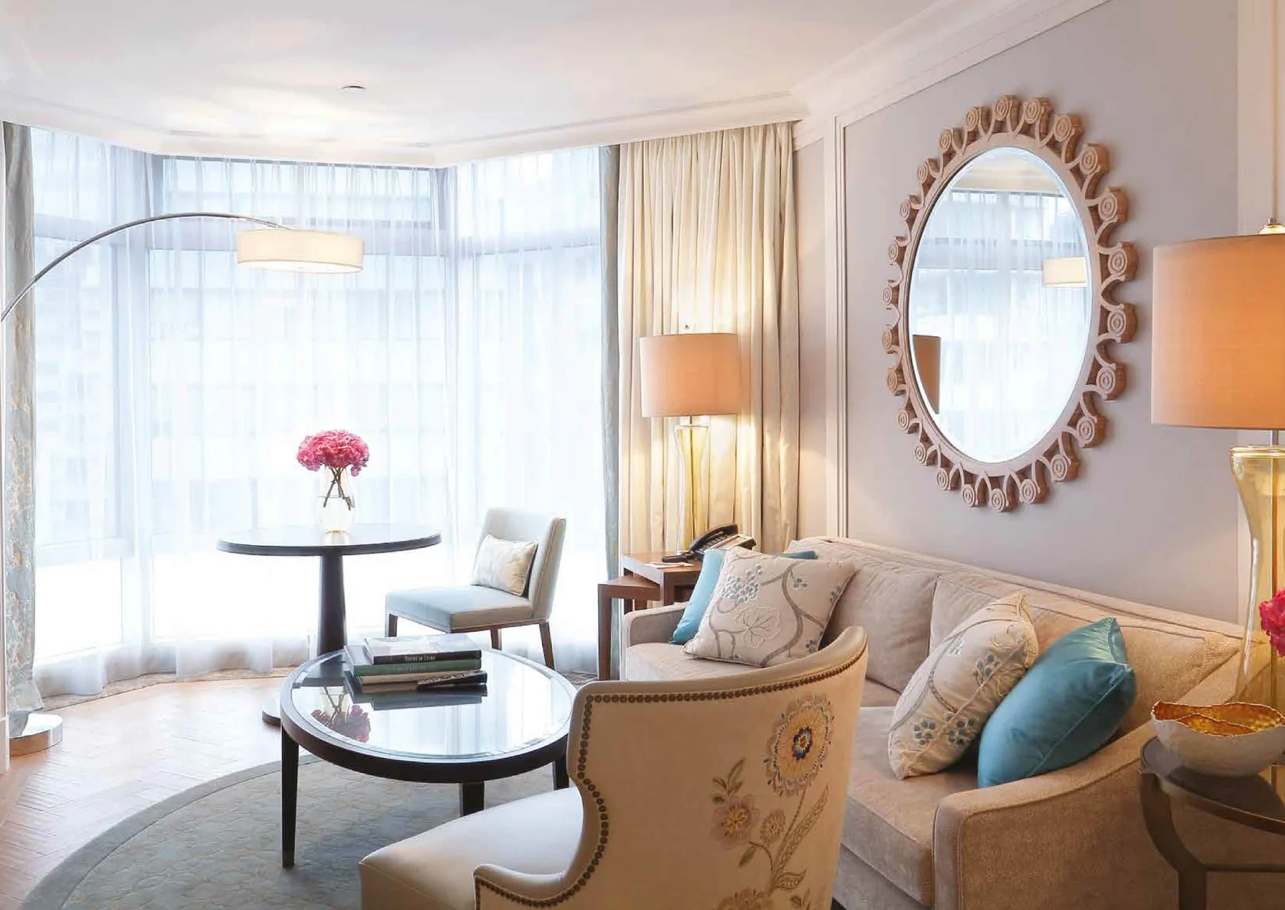 Hotel lounge with armchairs, side tables, lamps and curved mirror