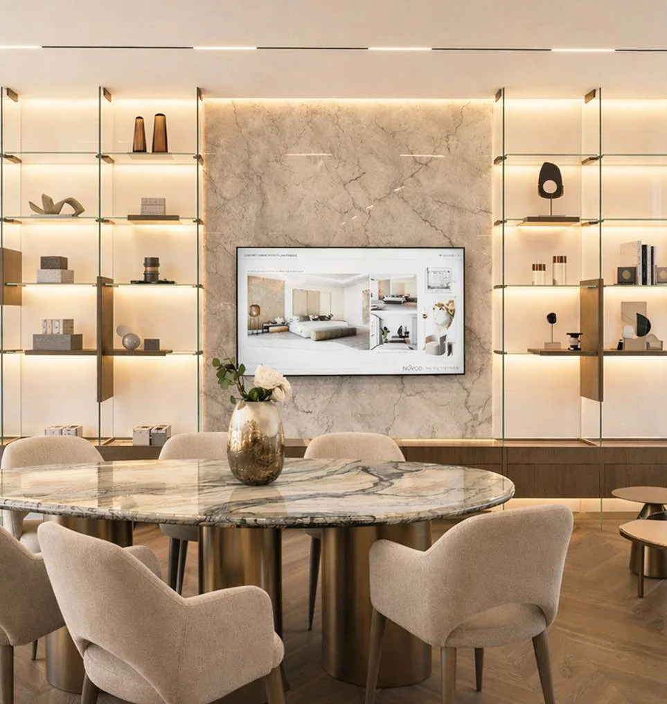 Upholstered dining chairs and a round table beside fitted display shelving
