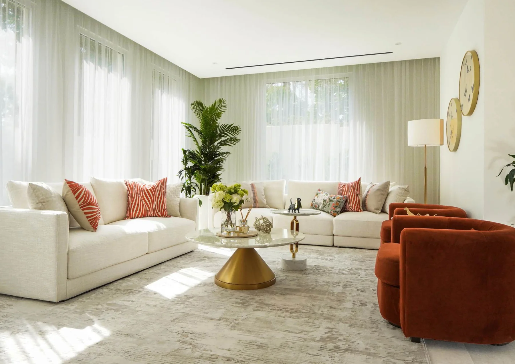 Sunlit living room with pale seating, coffee tables and full-height windows