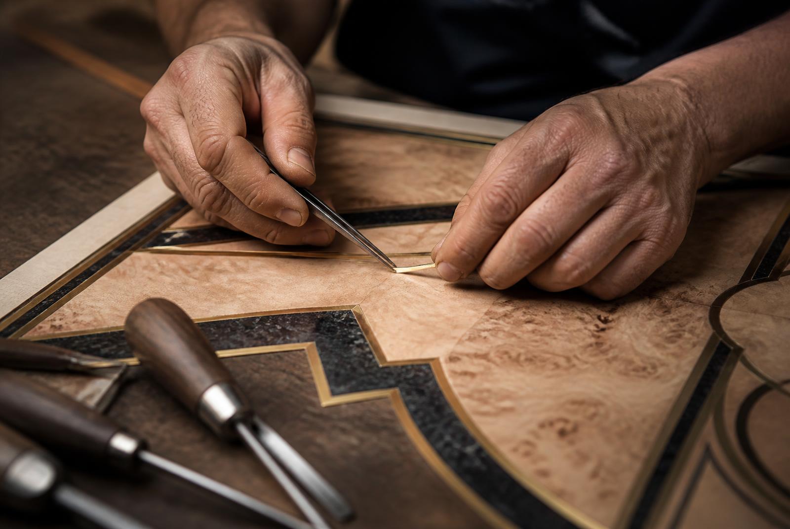 Hands setting a fine brass inlay into a marquetry panel