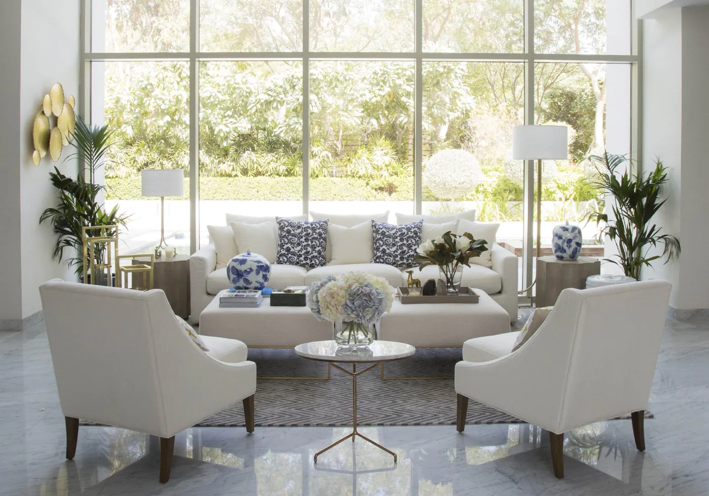 Furnished living room with white sofa, two armchairs and marble floor