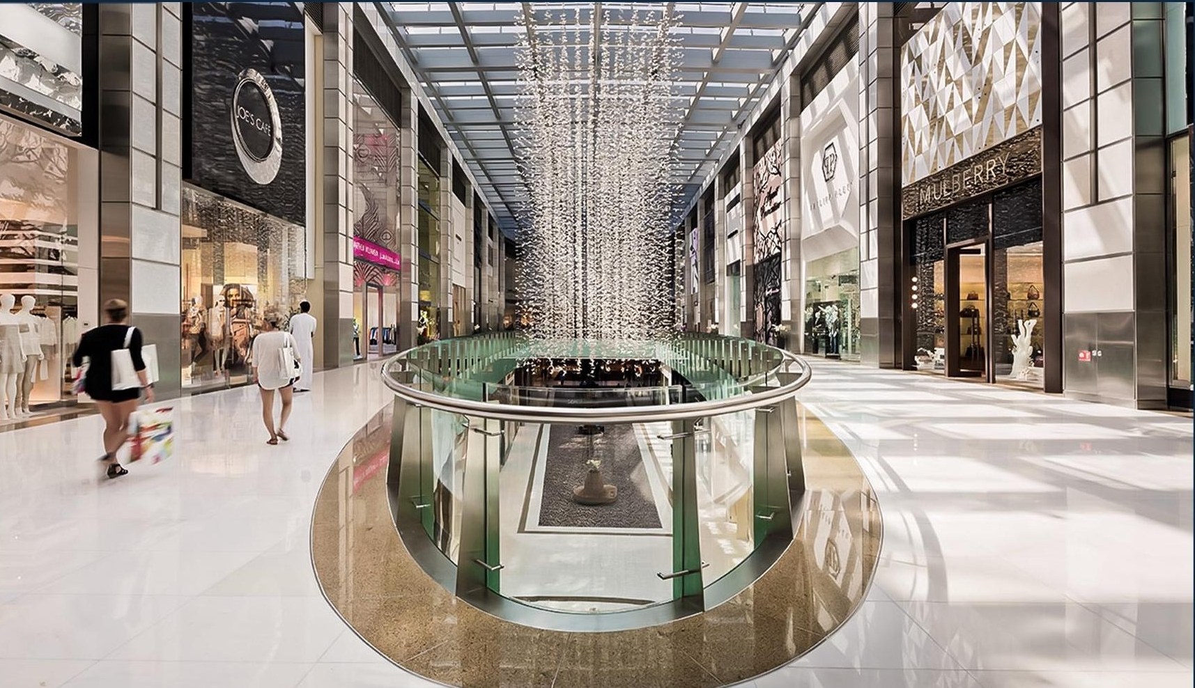 Mall retail avenue with marble floors, illuminated shopfronts and a central crystal feature