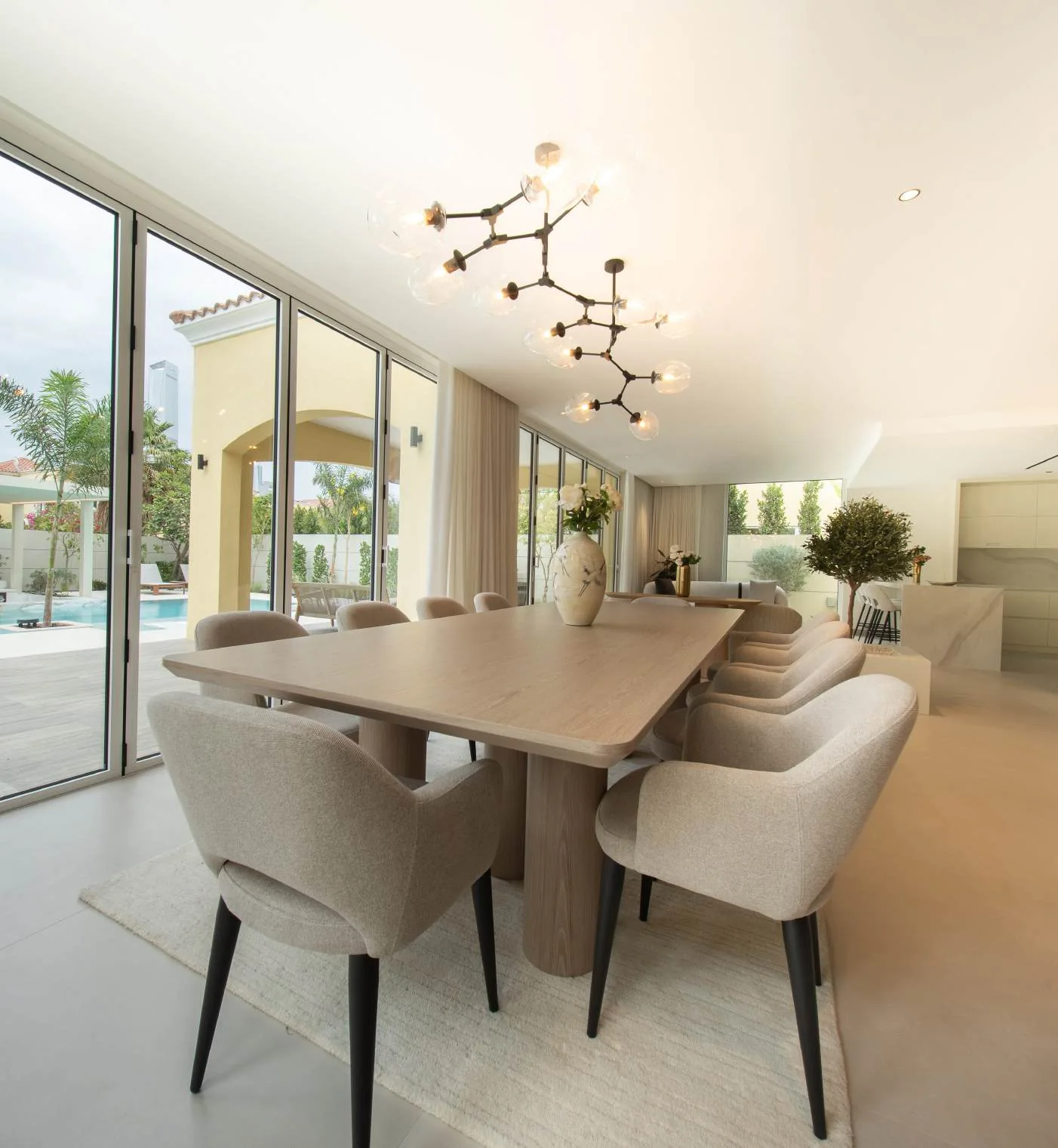 Sunlit dining room with upholstered chairs, pendant lighting and garden doors