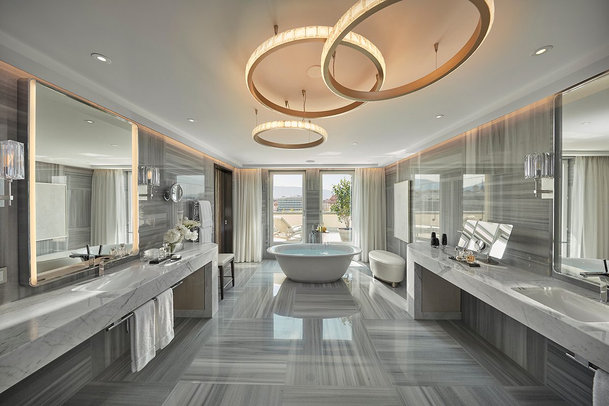 Penthouse master bathroom with book-matched grey marble walls and freestanding bath