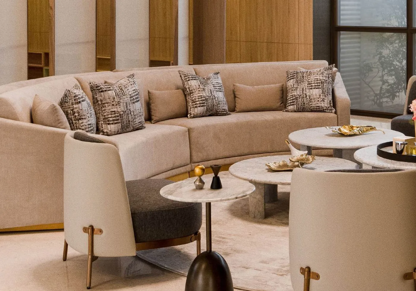 Lounge arranged with curved sofa, armchairs and grouped marble tables