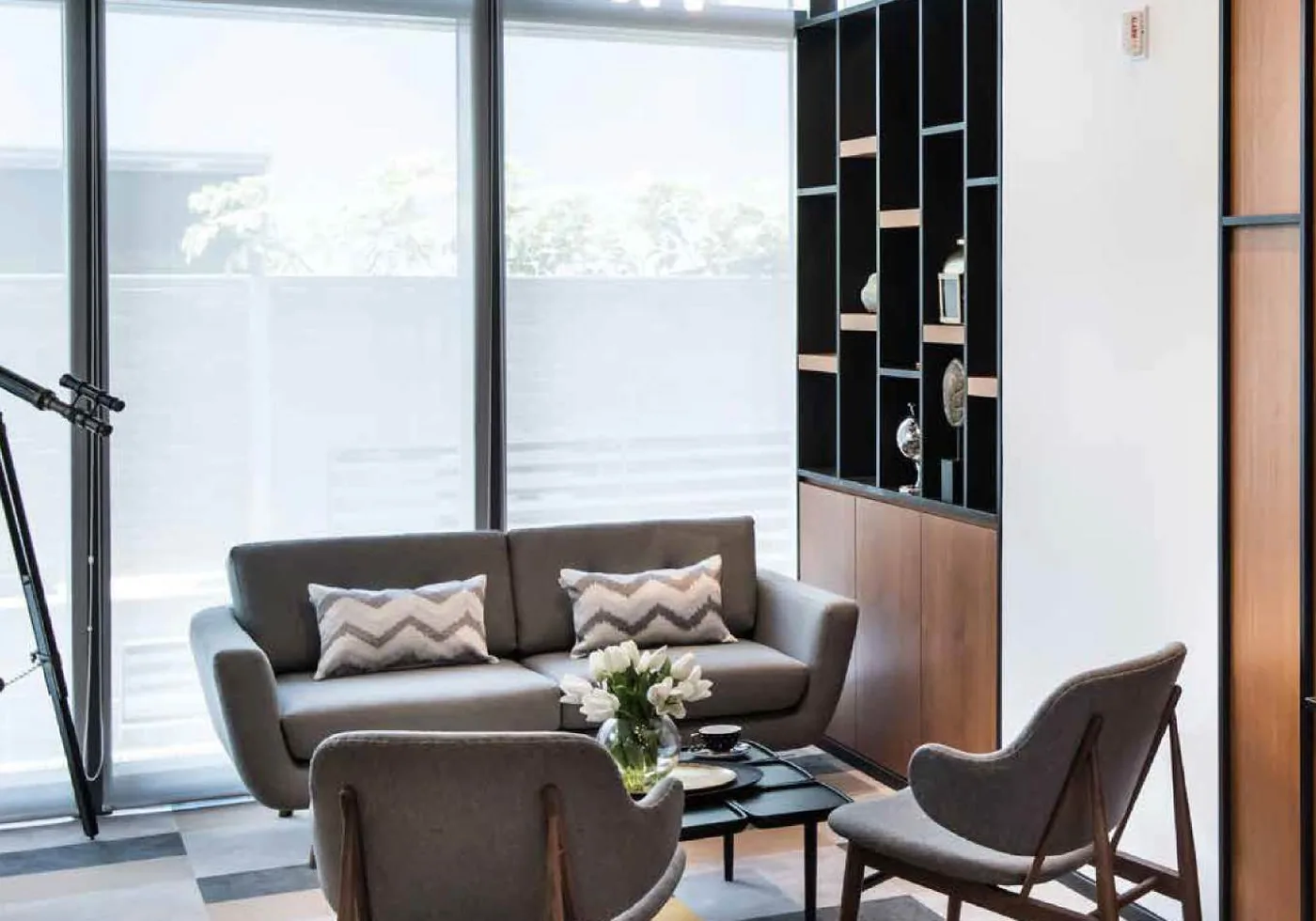 Compact workplace lounge with sofa, lounge chairs and fitted shelving