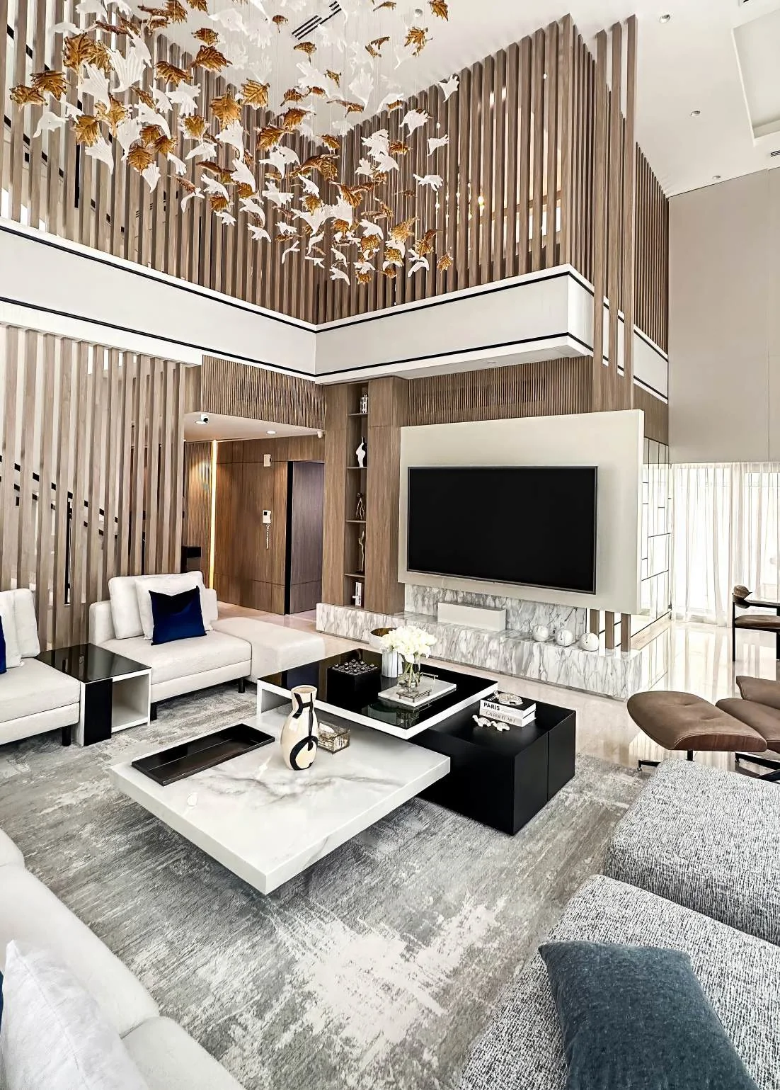 Double-height living and dining room with marble table and full-height windows
