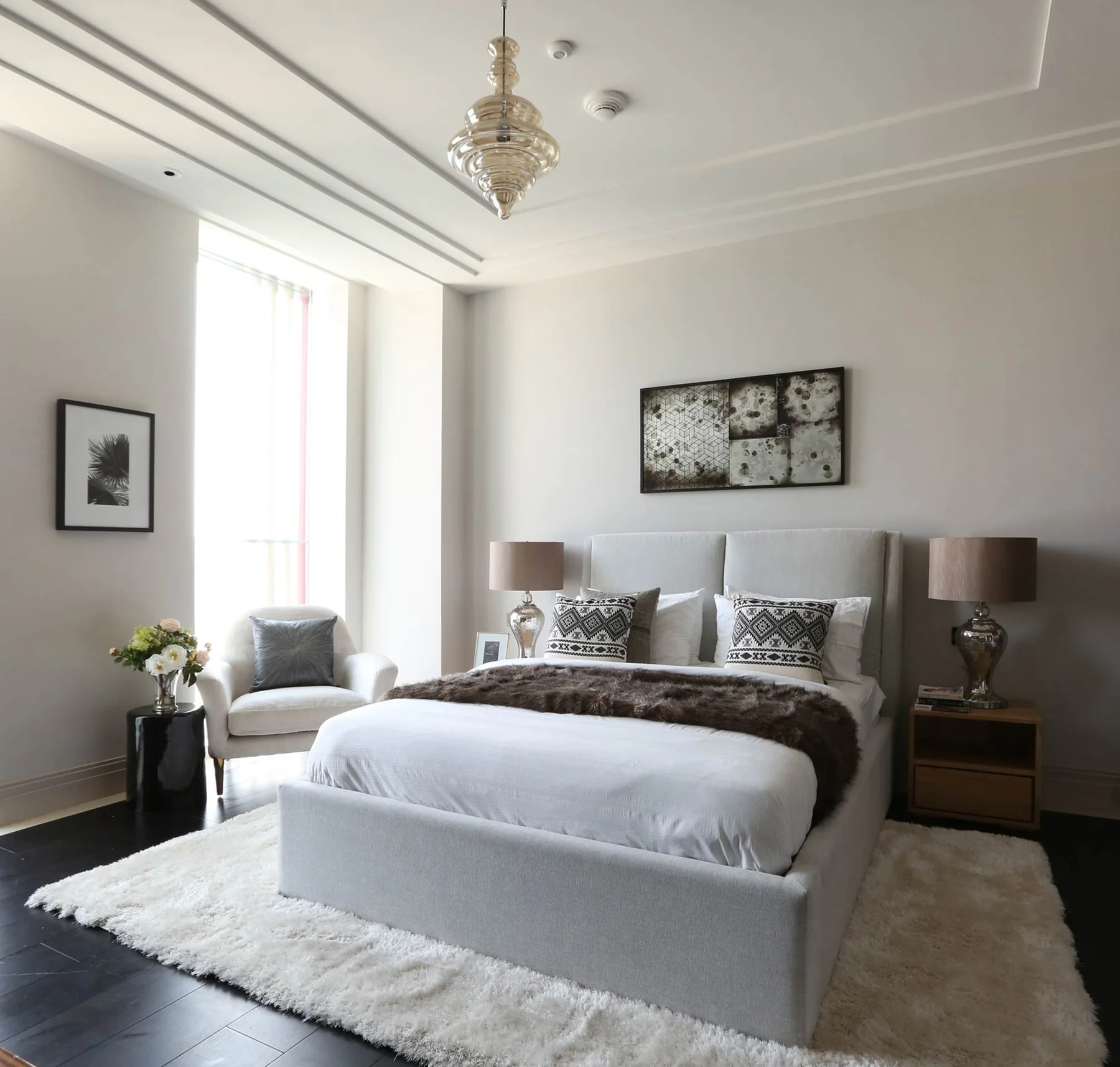 Hotel bedroom with upholstered bed, bench, bedside lights and lounge chair