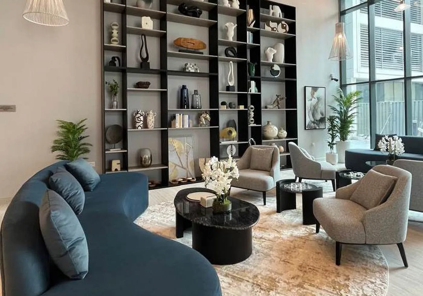 Furniture setting with curved blue sofa, armchairs and display shelving