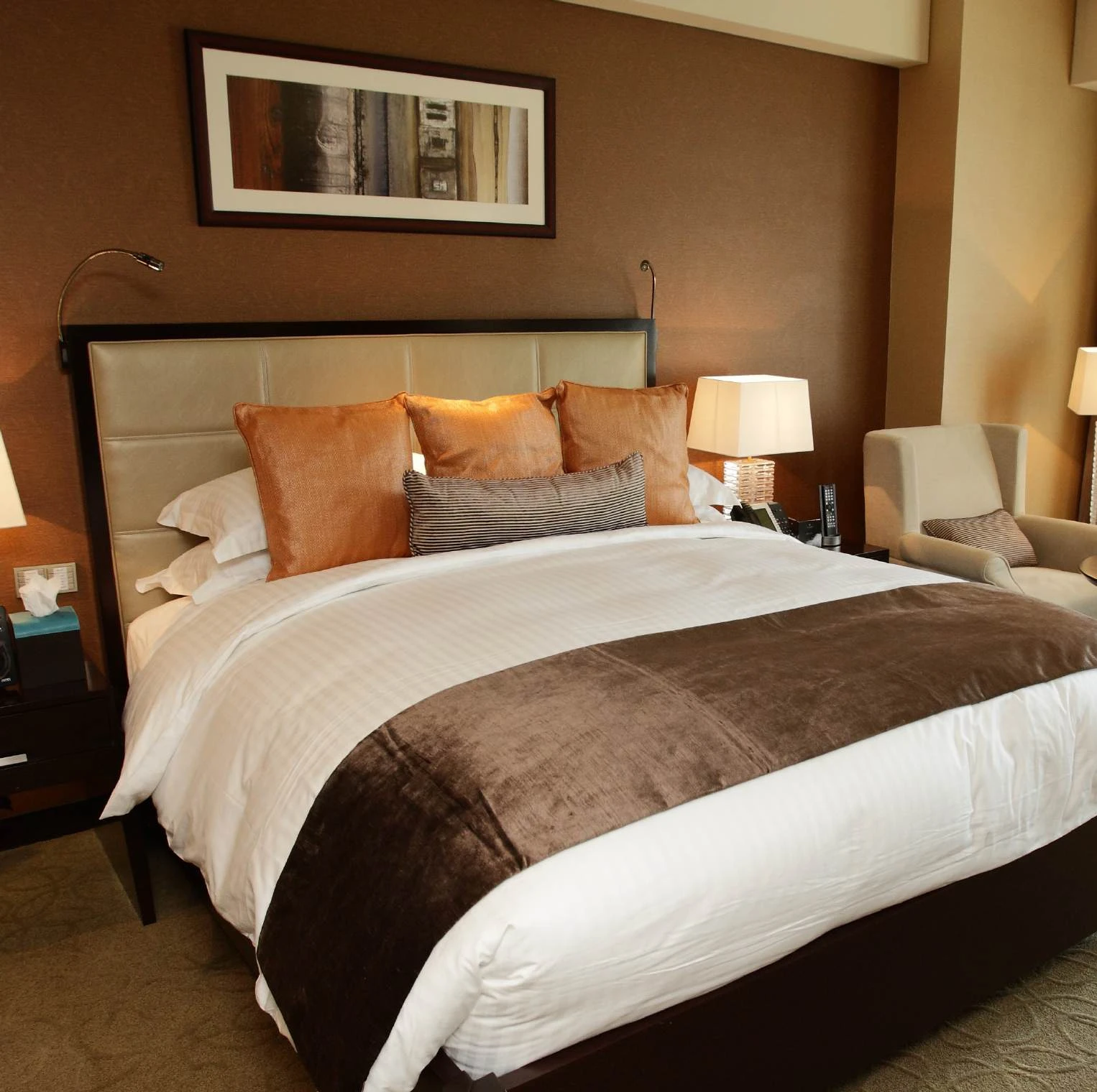 Upholstered bed with bedside furniture and a lounge chair