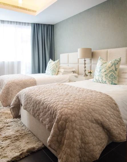 Twin beds with upholstered headboards and bedside lighting
