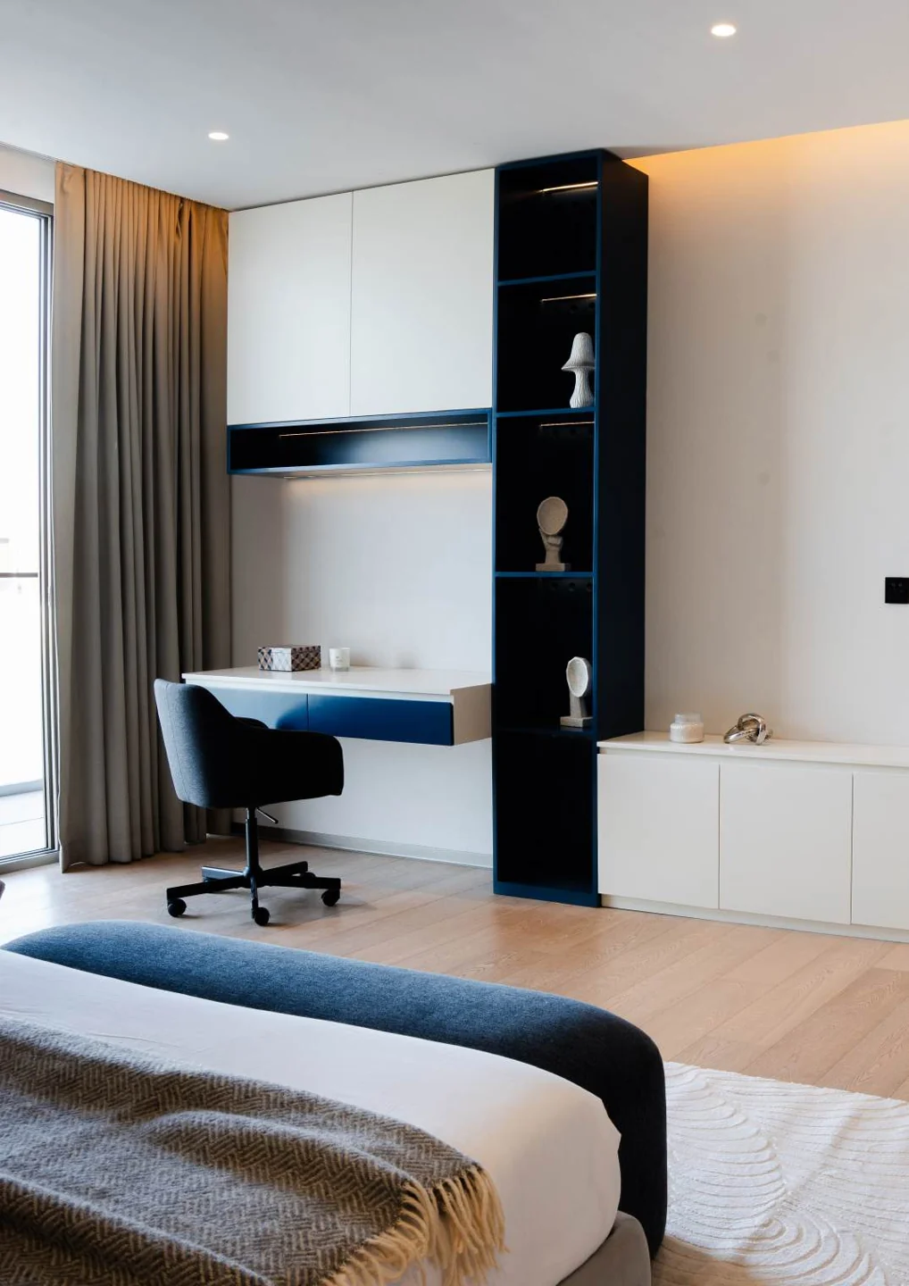 Built-in desk, shelving and closed storage beside a bed