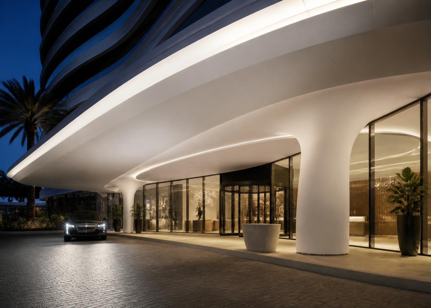 Curved white composite canopy soffit over a hotel entrance at dusk