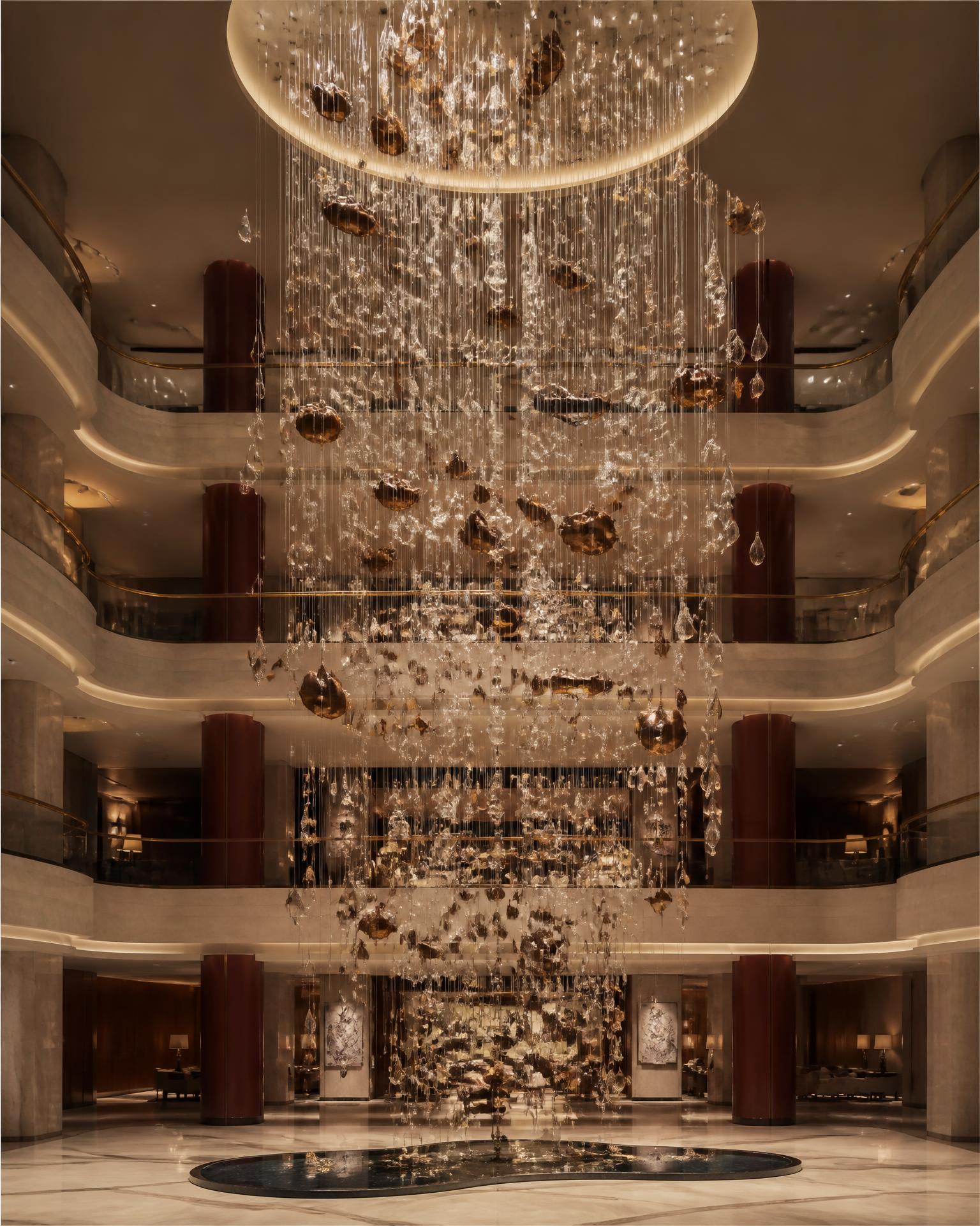 Large-scale chandelier installation rising through a luxury hotel arrival space