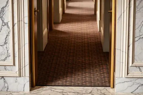 Marble meeting bespoke patterned carpet with brass trim in a hotel corridor